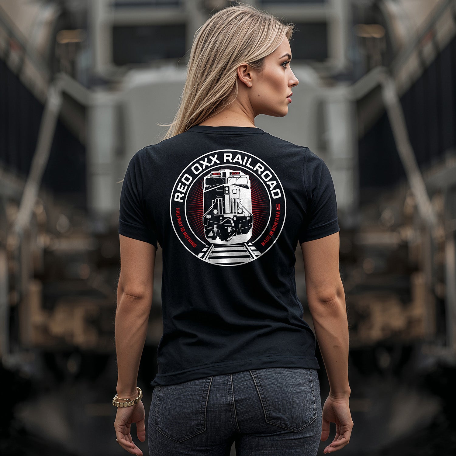 Person wearing a black t-shirt with a 'Red Oxx Railroad' logo in front of train tracks.