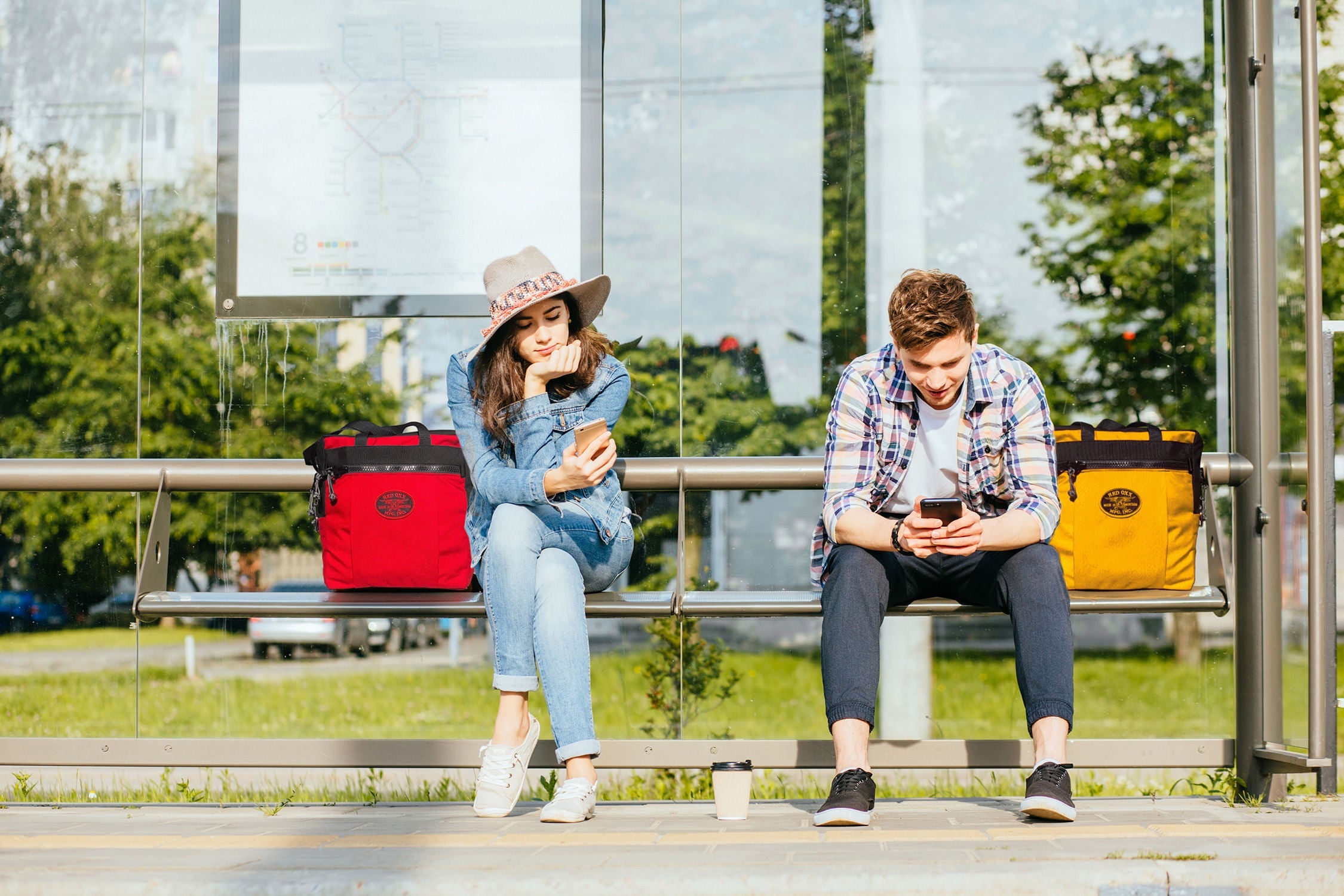 PUP young couple on phones at bus stop