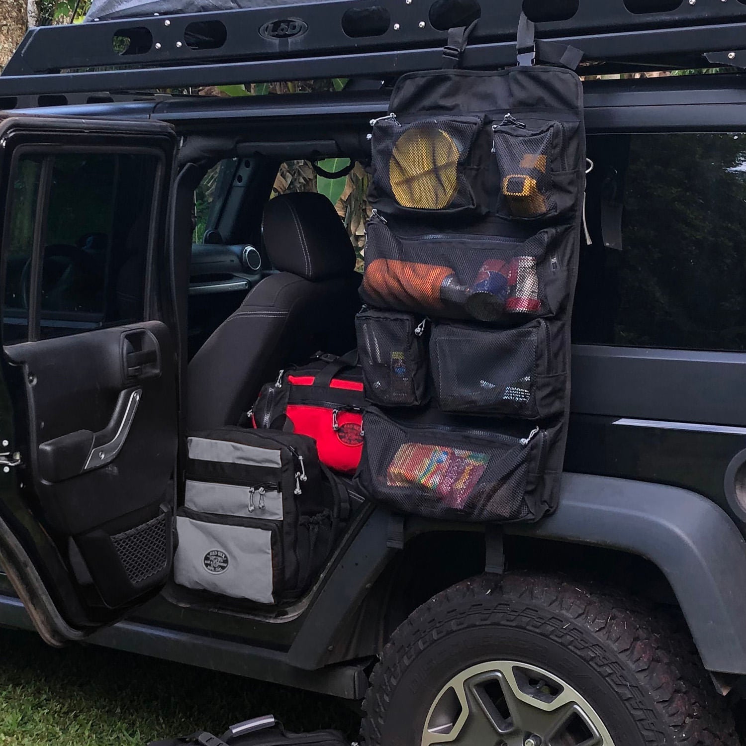Tool roll up hanging from roof rack of JEEP.  PR 5 Safari Beano bag in Red and K-5 Backpack in Coal color. 