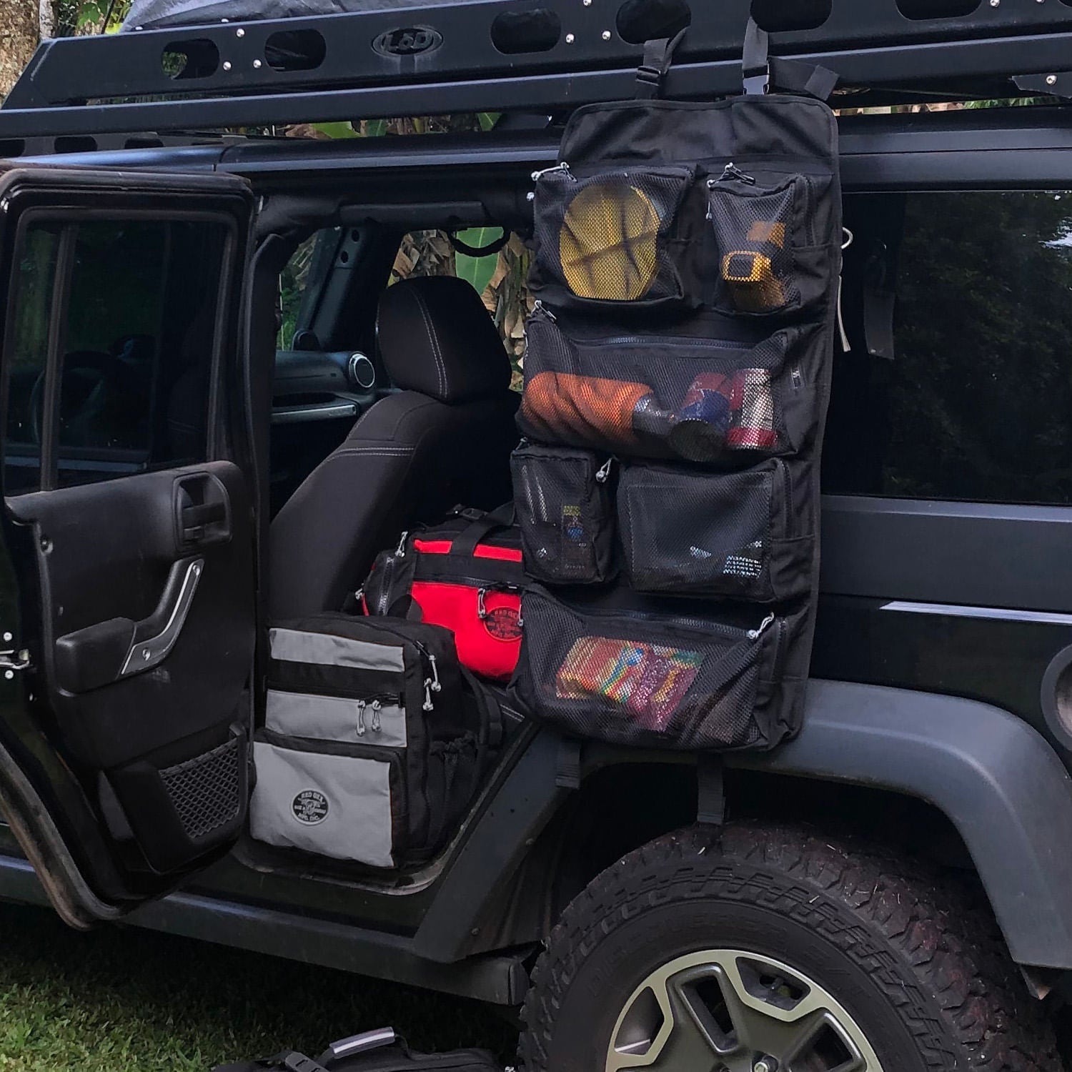 Tool roll up hanging from roof rack of JEEP. PR 5 Safari Beano bag in Red and K-5 Backpack in Coal color.