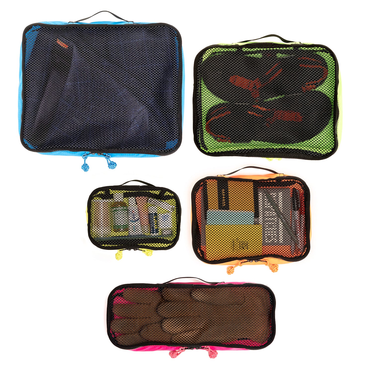 Overhead view of packing cubes with travel goods in each.  Kingfisher in blue has a pair of sweatpants, Bushbaby has a pair of sandals,Hedgehog is shown with toiletries, Armadillo is shown with notebook, pens and wallet. Meerkat is shown with leather work gloves. 